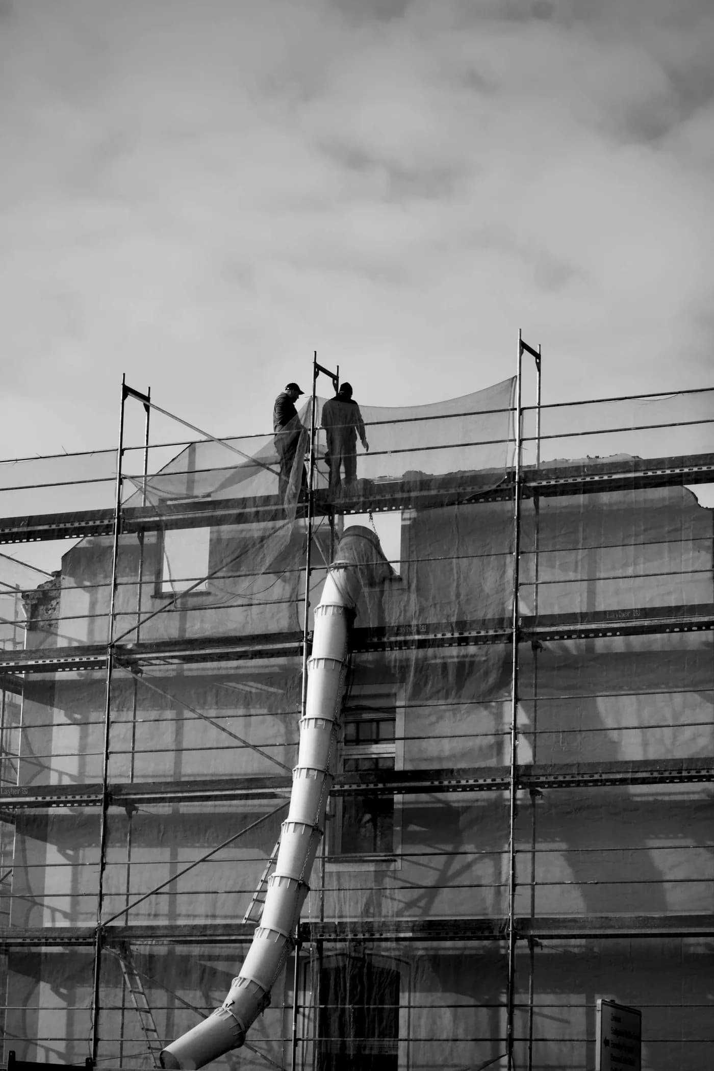 Black-and-white construction site with workers on scaffolding